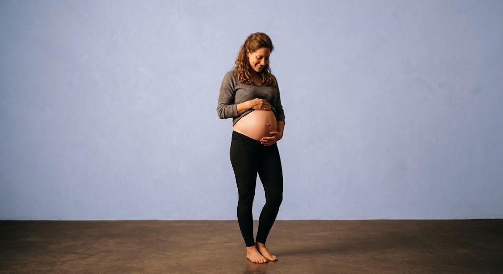 An expectant mother smiling down at her growing belly